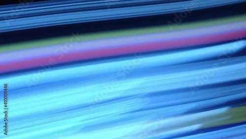 Abstract blue lines as an unusual background. Several glowing blue parallel lines of different thickness and shades. The pair of lines is pink and purple. Unobstructed blurred background. 