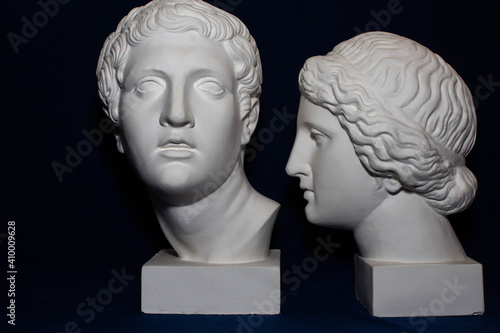 Two plaster heads of man and woman, old art, blue background 