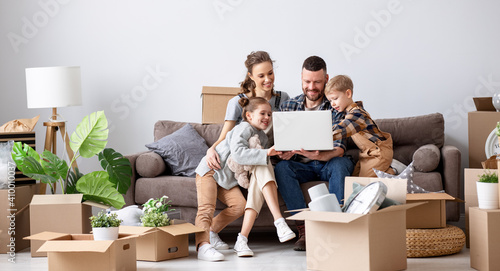Photography Smiling parents and children browsing laptop in new apartment
