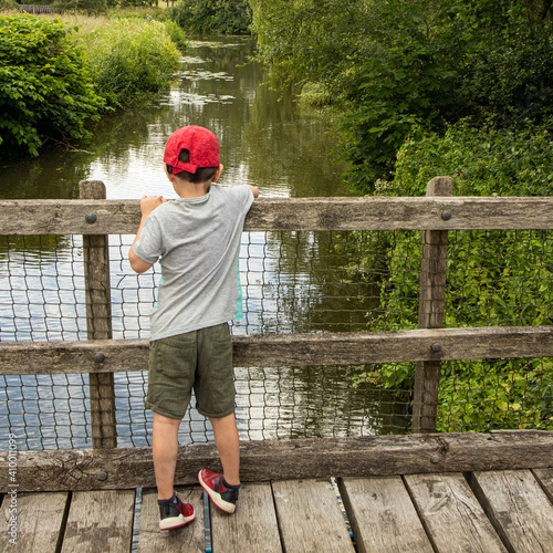 Child playing Pooh Sticks on a bridge over a river.