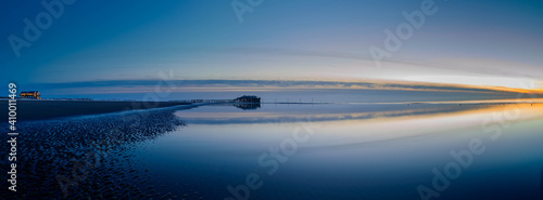 Foto Panorama view of splendid sunset at the Wadden sea of Sankt Peter Ording with stilt houses on the background, North Sea, North Friesland, Schleswig-Holstein, Germany