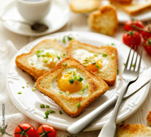 Valentine's breakfast, toast with a fried egg in the shape of a heart on a white plate, close-up.