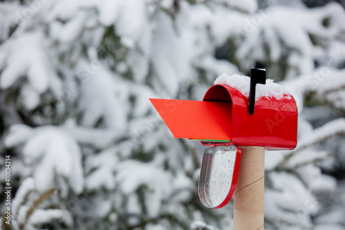 Red envelope in mailbox in a snow near pine tree in winter photo