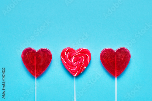 Valentines Day concept. Three Heart-shaped lollipop candies on a blue background. Copy space, top view.