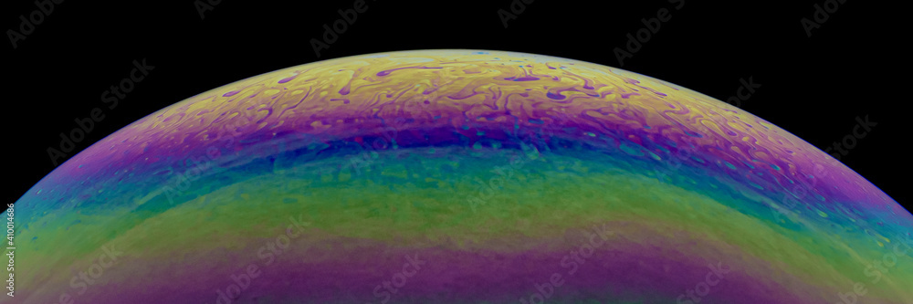 Obraz premium Close up, macro shot of a rainbow, multi colored soap bubble with yellow, purple, pink, blue and green colors on black background. 