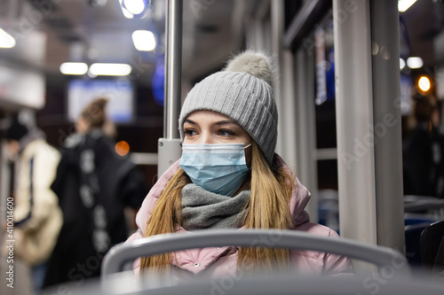 lonely girl in a face mask rides a tram at night in Pandemic time, Poland © Masson