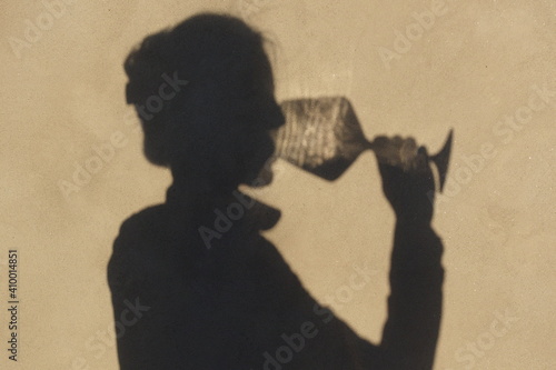 Shadow on the wall of a female sommelier alone with a glass of wine. Drink a glass of wine concept