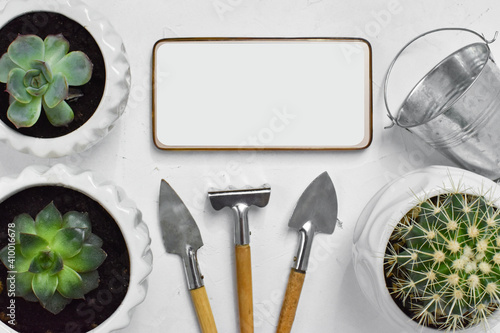 Online gardening courses. The background with the phone has a copy of the space. A variety of items for the care of plants. Flat lay. Top view. photo