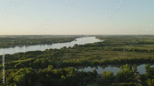 Aerial parallax of Zarate large green fields and forest area and Parana river flowing into horizon at golden hour, Entre Rios, Argentina photo