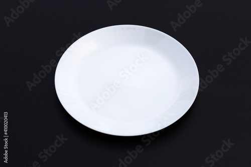 Empty white dish plate on dark background.