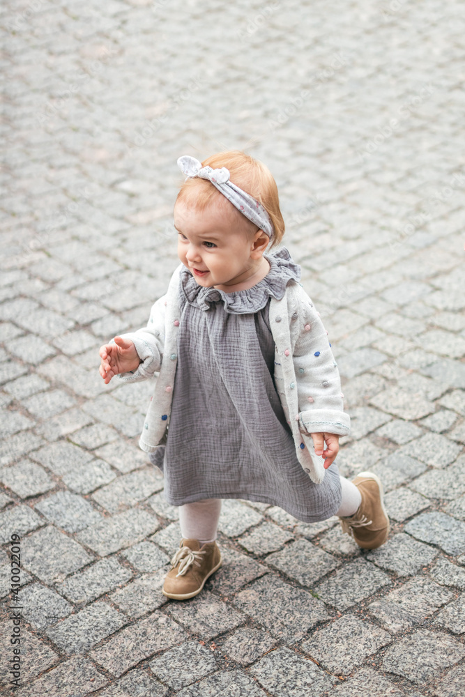 One year old baby girl in the mousline dress on the path in the park One year old baby girl in the mousline dress on the path in the park