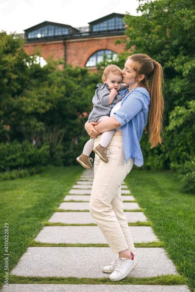 Fototapeta premium A young mother walks with a one-year-old baby. What to do while walking with your child
