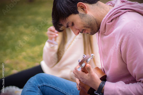 man playing a song to his girlfriend at picnic photo