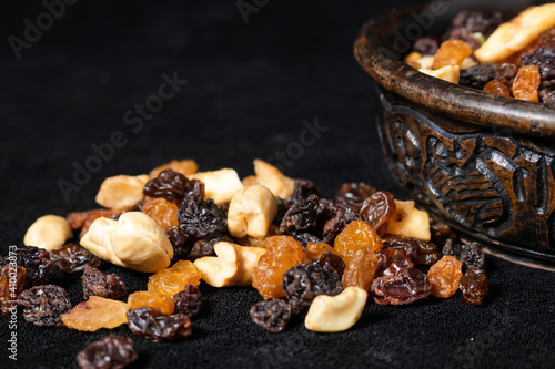 Mix of energetic seeds and dried fruits in a wooden bowl on a black surface. Close up. © HC FOTOSTUDIO