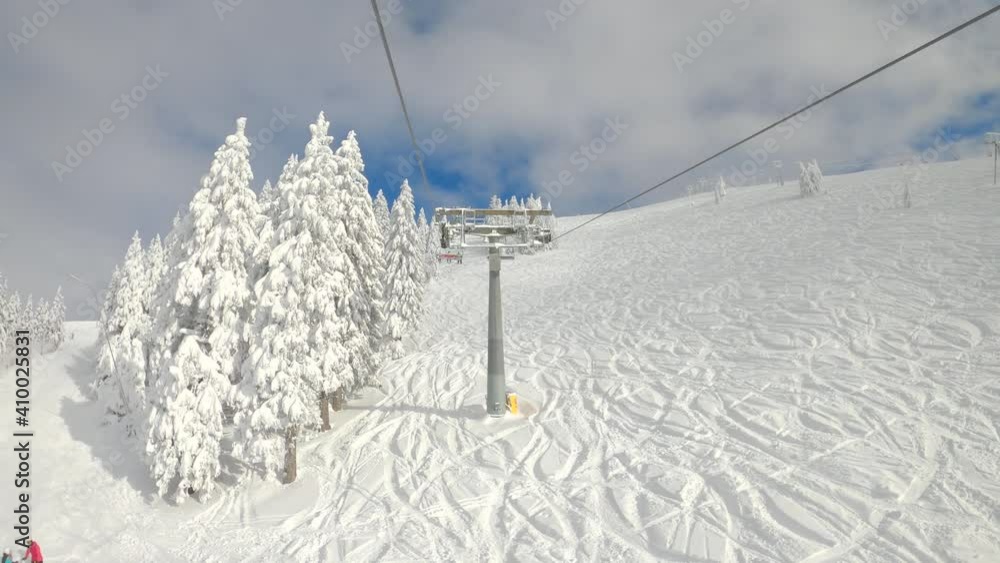 POV, TIMELAPSE, HYPERLAPSE: Scenic view of the ski resort while riding the chairlift up a crud snow slope. Chairlift ride over the tracked ski slopes towards the top of a mountain in the snowy winter. POV, TIMELAPSE, HYPERLAPSE: Scenic view of the ski resort while riding the chairlift up a crud snow slope. Chairlift ride over the tracked ski slopes towards the top of a mountain in the snowy winter.