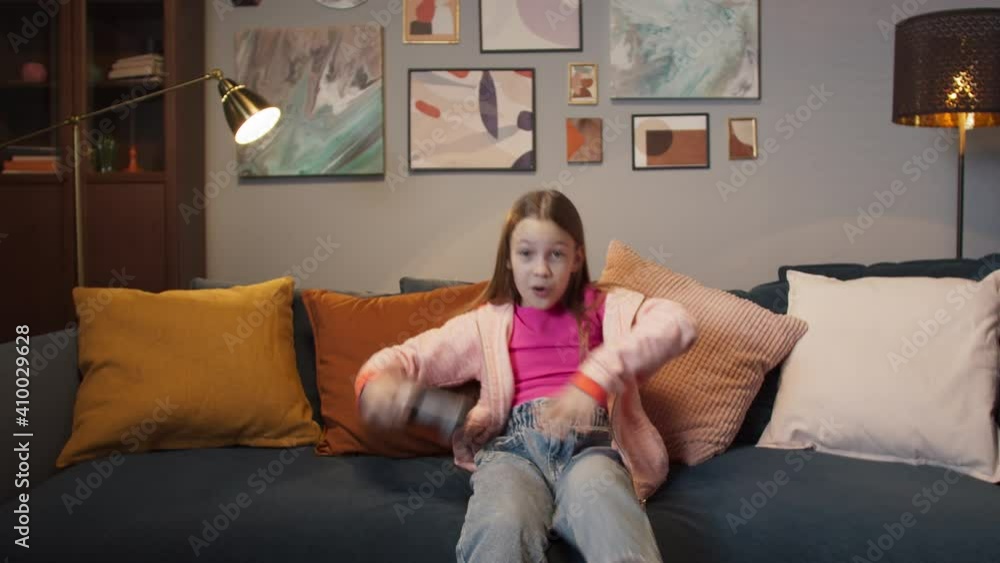 Pretty little girl are playing game console and laughing while sitting on sofa at home, next gen new generation games, happy after school, winner Pretty little girl are playing game console and laughing while sitting on sofa at home, next gen new generation games, happy after school, winner