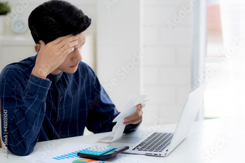 Young asian man calculating expenses household about finance and frustrated on desk at home, male checking bill having stress and worried, debt and tax, expression and emotion, business concept. © N_studio