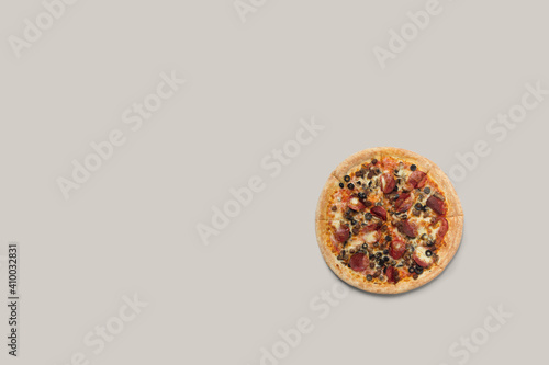 Delicious pizza and ingredients of sausage, bacon and mozzarella on a grey background. Top view of delicious pizza. photo