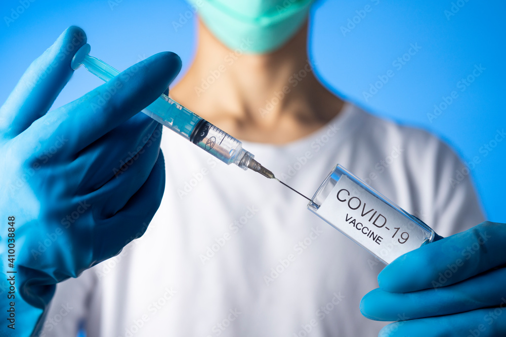 Doctor filling syringe with coronavirus covid-19 vaccine. on blue background Doctor filling syringe with coronavirus covid-19 vaccine. on blue background