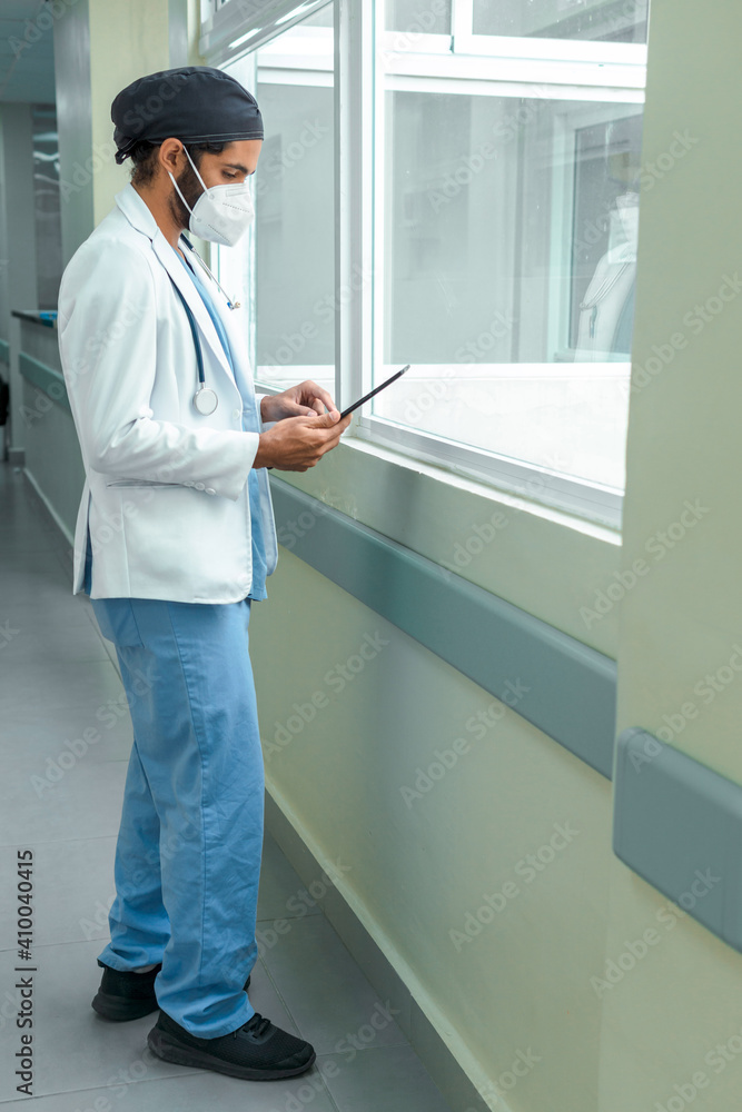 Doctor checking his tablet in the corridor of a hospital Doctor checking his tablet in the corridor of a hospital