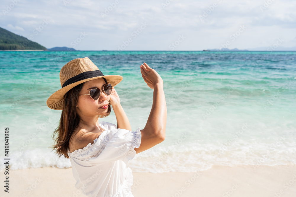 Young woman traveler wearing sunglasses covering face by hand to protect UV rays from the sun at tropical sandy beach on sunny day, Skin care and eyes protect concept