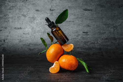 Balancing tangerines and aroma oils on a dark background. Fresh tangerines. Trending style Balance and levitation.