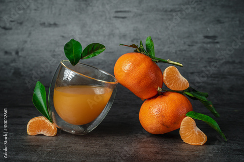 Glass of juice with tangerines on a black background. Trending style Balance and levitation.