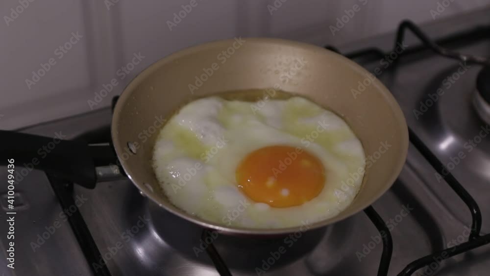egg being fried in butter in skillet for breakfast