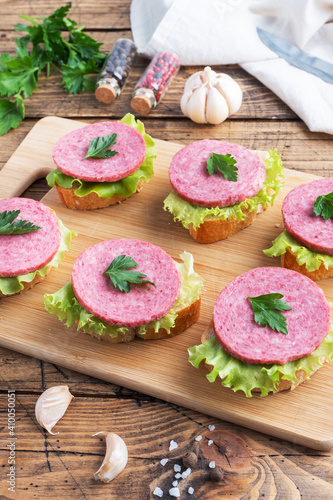 Sandwiches with lettuce leaves and sliced salami sausage on a wooden Board.