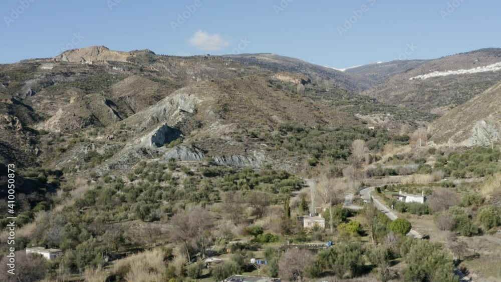 Hilly mountainside with blue skies and sparse houses dotted around. Hilly mountainside with blue skies and sparse houses dotted around.