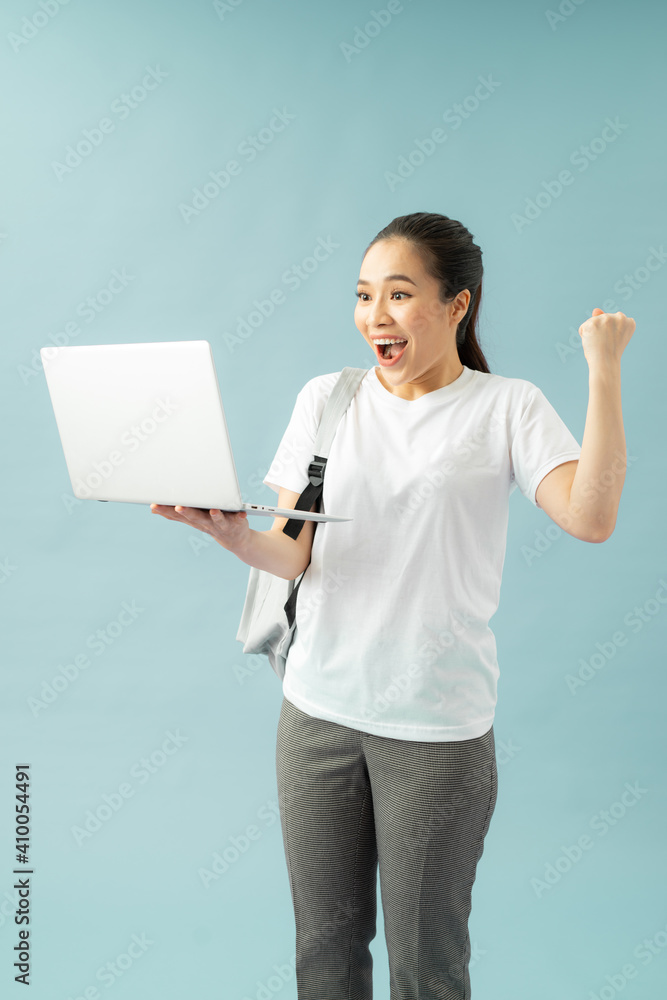 Portrait of a young smilling student girl on a blue background.
