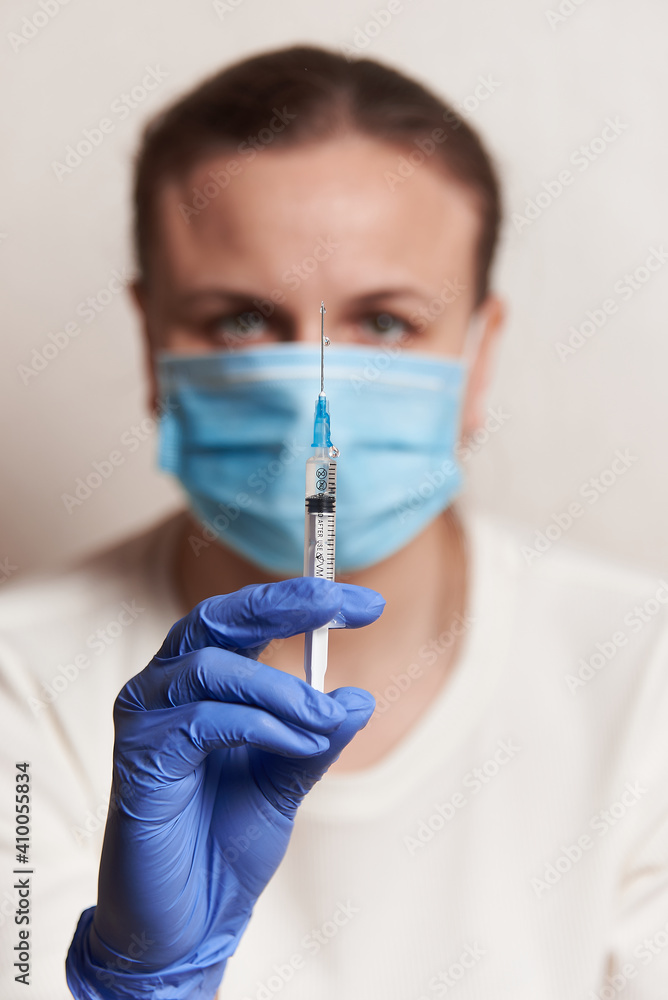 a woman holds an injection syringe in front of her. Vaccination in a pandemic a woman holds an injection syringe in front of her. Vaccination in a pandemic