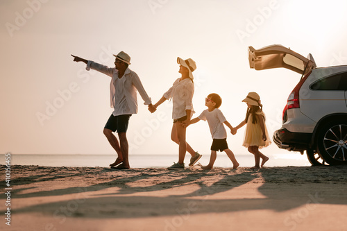 Asian family on the beach.Vacation time. Happy father, mother and son enjoying road trip the summer holidays.Parents and children are sitting on a hatchback with a sea background. photo