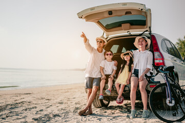 Happy asian family enjoying beach trip with their favorite car. Parents and children are traveling the way to the sea.Holiday and travel family concept, Summer vacations.