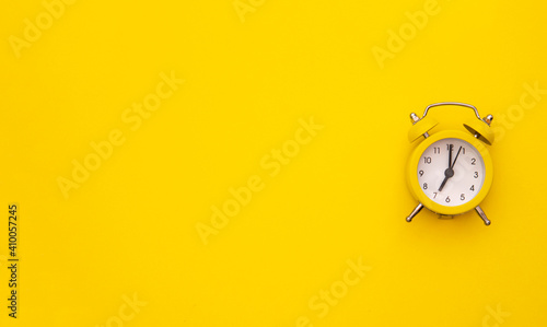 Yellow alarm clock on a yellow background. Morning. Classic watch. The clock is seven o'clock. Time will wake up. Classic watch style. 
