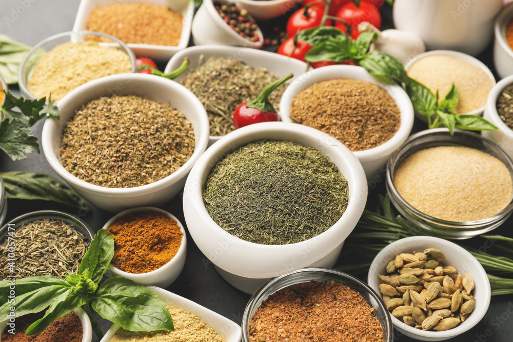 Bowls with different spices and herbs on dark background, closeup Bowls with different spices and herbs on dark background, closeup