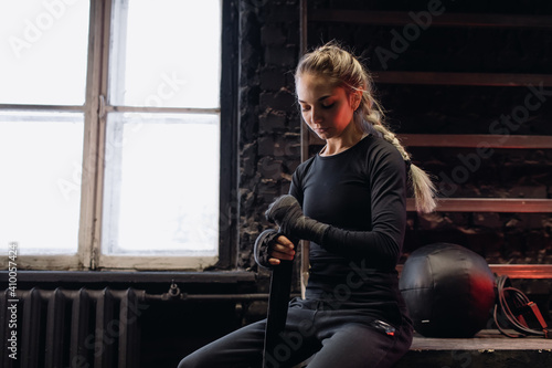 Girl fighter bandages her hands before training in the gym. Red Neon Light