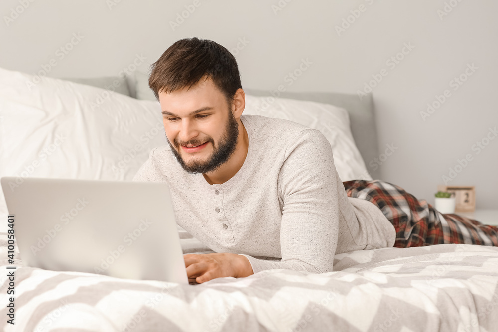 Young man with laptop in bedroom Young man with laptop in bedroom