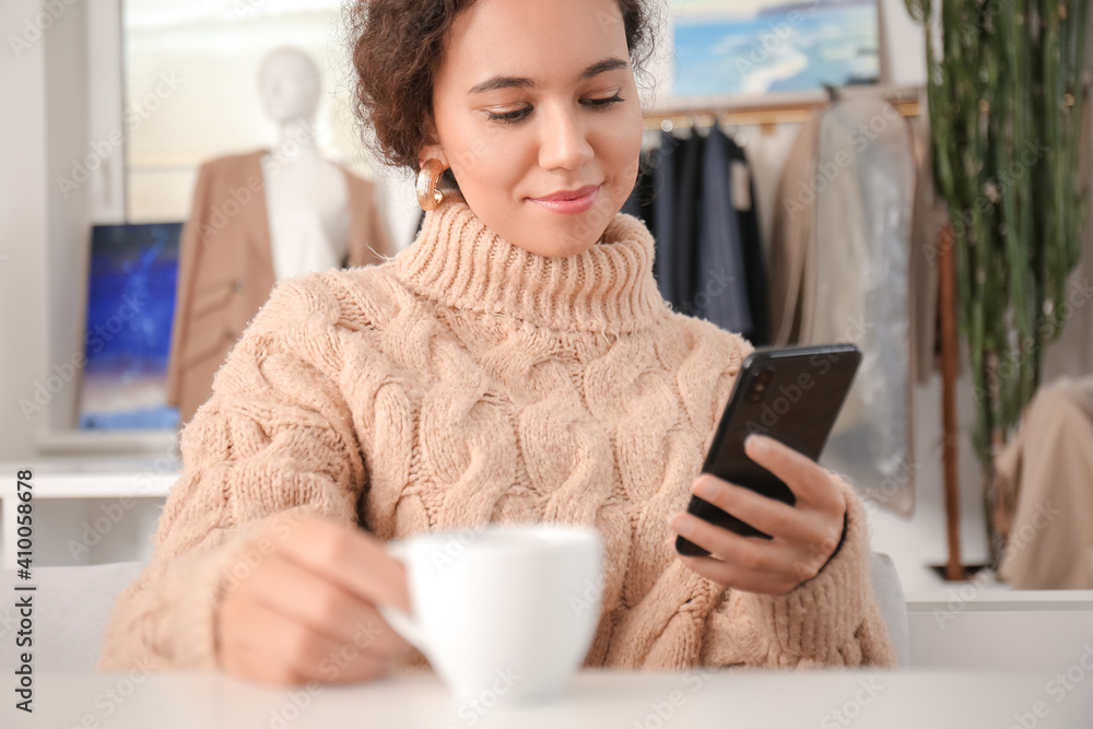 Beautiful woman with mobile phone and cup of hot espresso in cafe Beautiful woman with mobile phone and cup of hot espresso in cafe