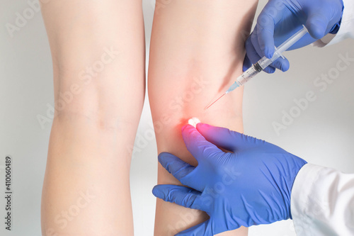 The doctor makes an injection into the periarticular tissue, in which there is pain behind the knee and intravascular pathologies, close-up © HENADZY