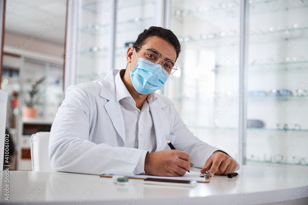 Eye doctor with a pen in one hand staring ahead Eye doctor with a pen in one hand staring ahead