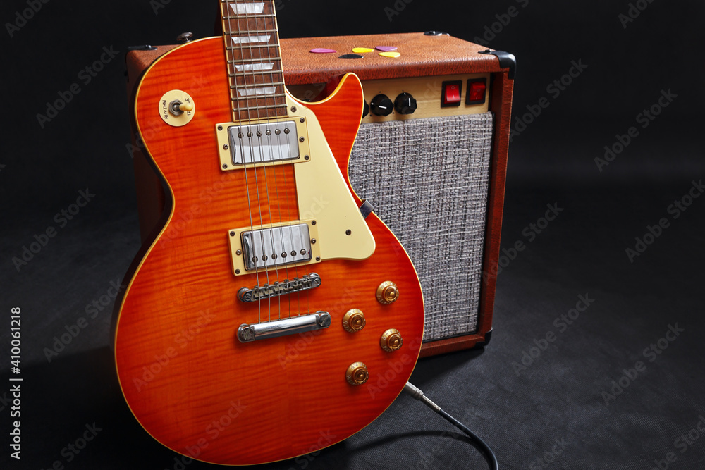 Fototapeta premium Combo amplifier for guitar with honey sunburst guitar on black background.