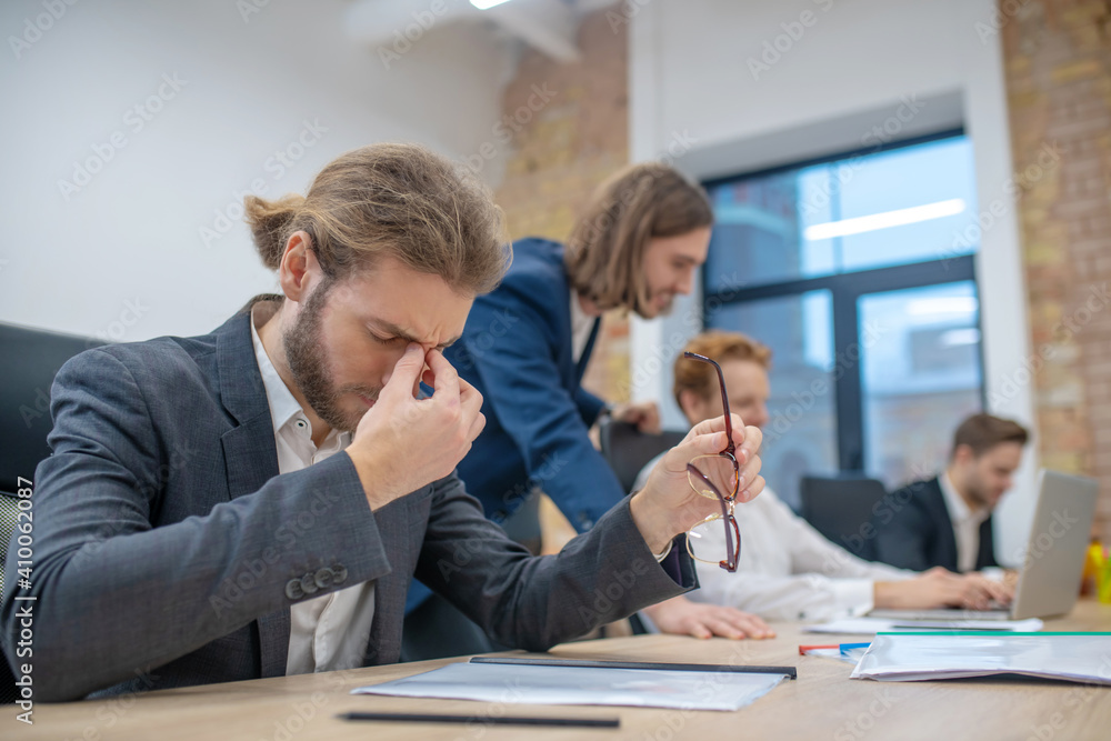 Obraz premium Tired man with closed eyes sitting in office