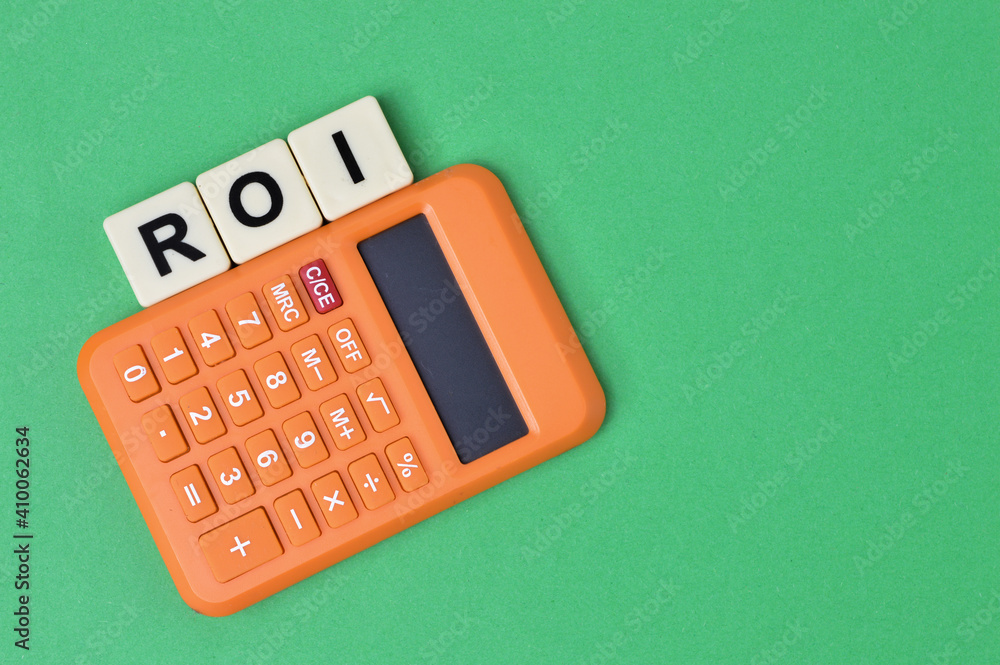 Top view of calculator and scrabble letters with text ROI stands for Return On Investment. Top view of calculator and scrabble letters with text ROI stands for Return On Investment.