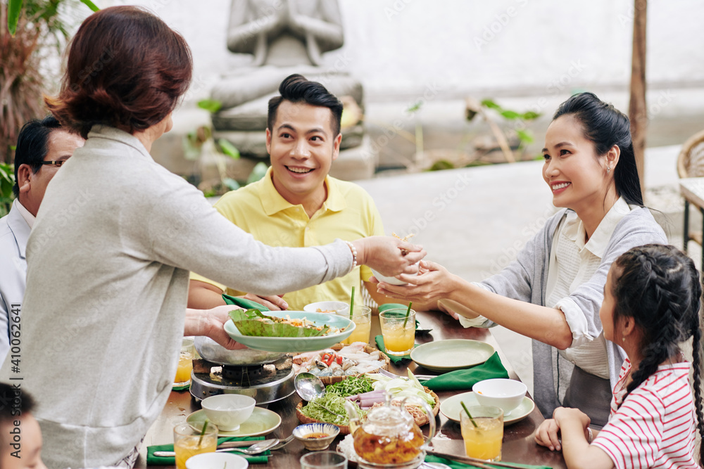 Senior woman serving dinner for her big family celebrating Lunar New Year together