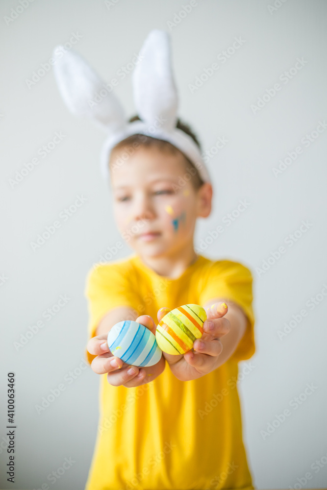 Portrait of smiling boy with bunny ears keeping colored eggs for Easter in art studio, copy space. Preparing for Easter. Portrait of smiling boy with bunny ears keeping colored eggs for Easter in art studio, copy space. Preparing for Easter.