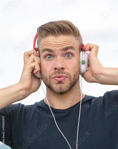 Excited Man listening music in headphones. Emotional surprised portrait guy. Young bearded casual man with and earphones.