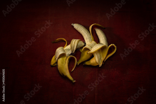 Foto Sex position of three yellow ripe bananas on a dark red wooden background
