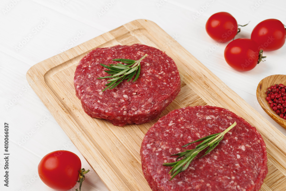 Two raw beef burger patties on wooden board Two raw beef burger patties on wooden board