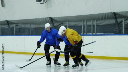 Two hockey players helping their injured teammate to stand up and leave ice rink